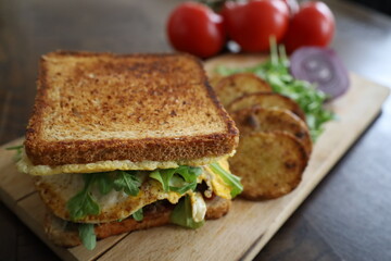 delicious toasted club saandwich with vegetables dressing and baked potatoes on a wooden board