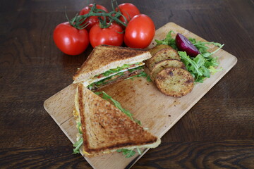 upper view of delicious toasted club saandwich with vegetables dressing and baked potatoes on a wooden board