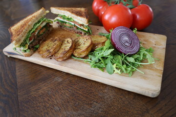 homemade club sandwich with vegetables and baked potatoes