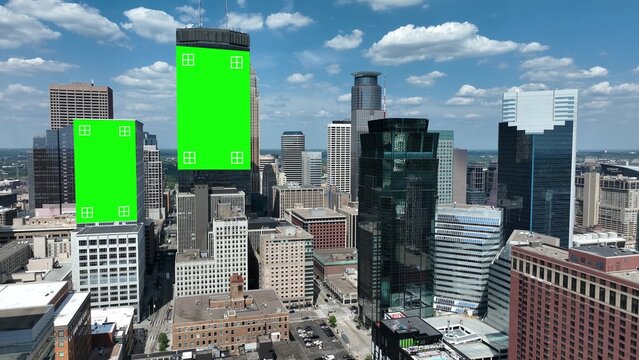 Skyline with buildings and green screens for advertisement. Aerial shot in modern American city against blue sky with puffy clouds