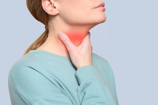 Endocrine system. Woman doing thyroid self examination on grey background, closeup
