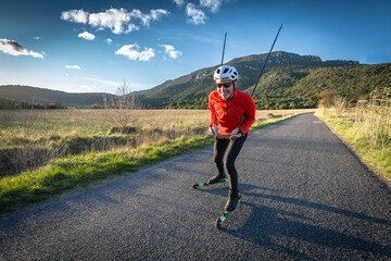 un homme sur des ski-roues à la campagne  sur une route goudronnée