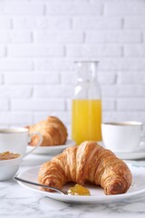 Tasty breakfast. Fresh croissant and jam on white marble table