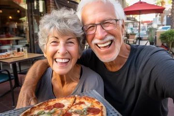 Foto op Aluminium Happy senior old couple have fun eating a pizza together outdoor in traditional italian pizzeria restaurant sitting and talking and laughing. People enjoying food and elderly lifestyle. Tourism © simona