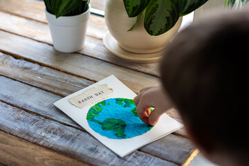 Children's craft for the Earth Day celebration. Little boy holding handmade simple postcard with a...