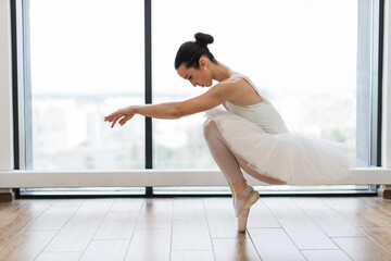 Classical Caucasian Ballet dancer side view. Beautiful graceful ballerina in white practice ballet...