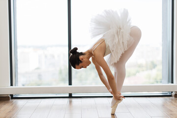 Classical Caucasian Ballet dancer side view. Beautiful graceful ballerina in white practice ballet...