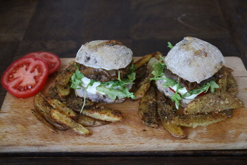 two delicious homemade rustic burgers with fries on wooden table