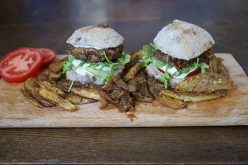 two delicious homemade rustic burgers with fries on wooden table