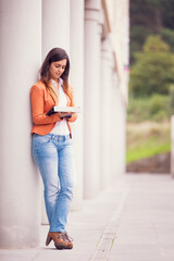young businesswoman in professional attire, utilizing a tablet in an outdoor setting - 750972288