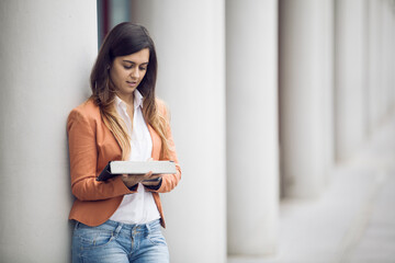 young businesswoman in professional attire, utilizing a tablet in an outdoor setting - 750972293
