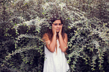beautiful woman in a white dress, gracefully posed amidst lush green vegetation - 750972443