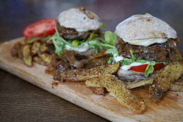 home made rustic mini burgers and baked potatoes on wooden board