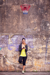 young woman leaning against a graffiti-covered wall in an urban setting - 750972488