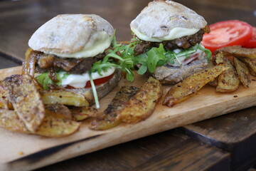 home made rustic mini burgers and baked potatoes on wooden board
