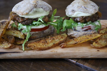 closeup homemade rustic mini burgers and baked potatoes on wooden board