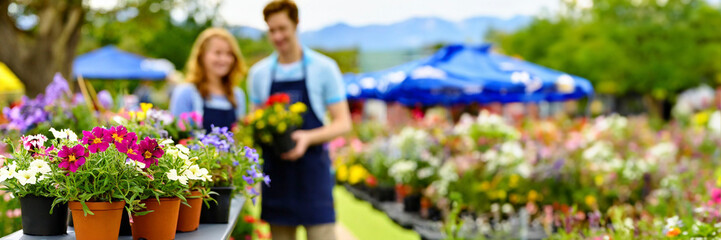 Couple working in garden center with colorful flowers in pots for sale in spring summer season