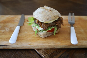 home made rustic mini burger and baked potatoes with fork and knife  on wooden board