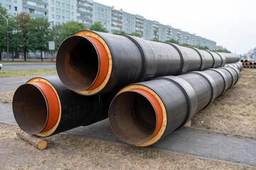 Steel pipe with heat insulation. New black insulated steel pipes at municipal construction site outdoors. Heating main district pipeline renewal or reconstruction.