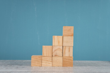 wooden block stacking as step stair on blue background. Business concept for growth success process.