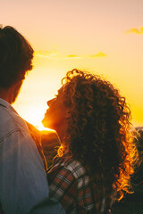 Love and romance outdoor leisure activity with man and woman hugging during golden sunset in...