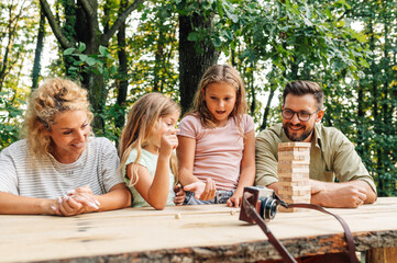 Fototapeta premium A playful girls playing jenga game with parents in nature.