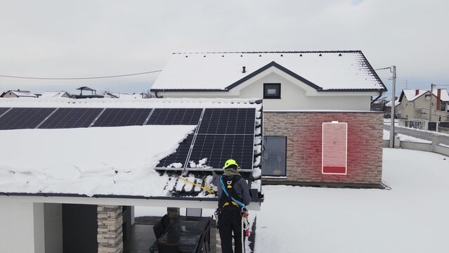 Smart House With Low Battery Icon In Winter. Technician Repairing Solar Panels On Roof Damaged By Snow. Graphic