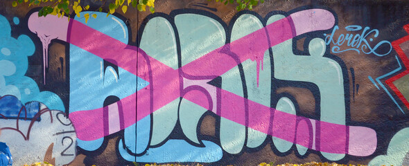 The old wall decorated with paint stains in the style of street art culture. Colorful background of full graffiti painting artwork with bright aerosol outlines on wall. Colored background texture