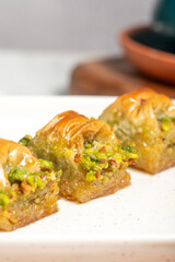 Cimcik baklava. Mediterranean cuisine flavors. Pistachio baklava with turkish coffee on rustic table, ramadan or holiday desserts concept. Close up
