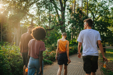 Four urban gen z friends walking in park and drinking tea and coffee.