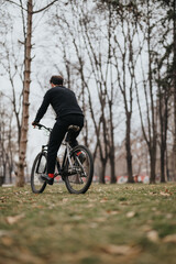 A businessman enjoying a leisurely bike ride through a tree-lined park, balancing work-life and health.