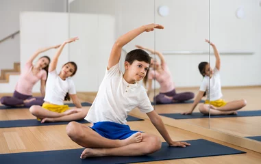 Fotobehang Young boy exercising lotus pose with his family during group yoga training. © JackF