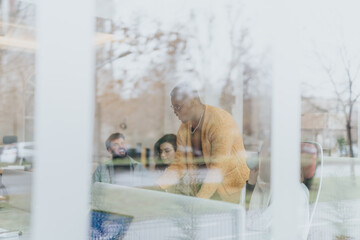 Multicultural colleagues collaborating indoors in a creative office. Creative people exchanging ideas and discussing reports. International team strategizing for profit and revenue growth.