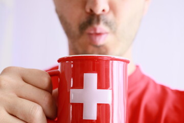 casual bald man holding a switzerland flag printed mug ,swiss coffee and chocolate beverage...