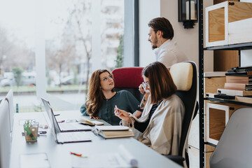 Young employees collaborating in a modern office. Discussing project solutions with happy and successful results.