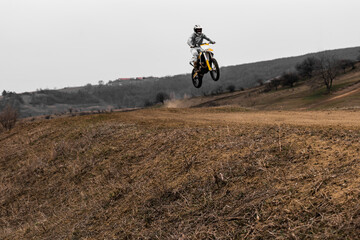 Person jumps on motocross bike with helmet into the sky