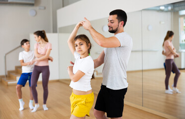 Fototapeta na wymiar Young girl dancing with her dad during rehearsal in gym.