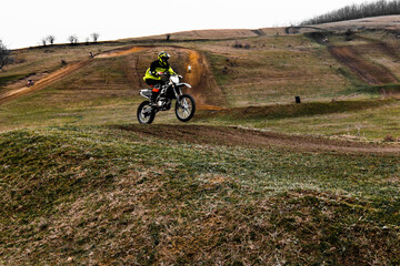 Rider on motocross bike with helmet races on dirt track