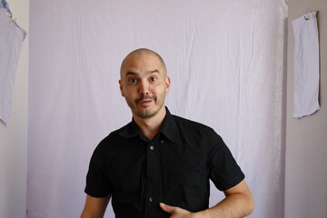 bald man in black shirt showing emotion and making gesture , funny face