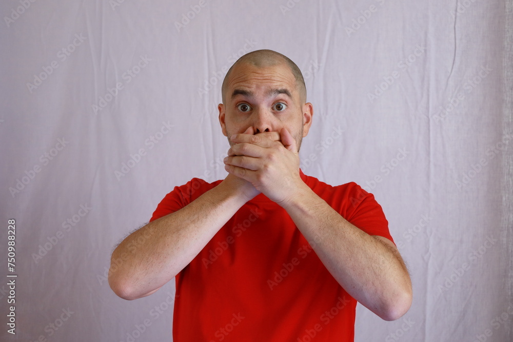 Wall mural casual bald man in red shirt making hand gestures covering his mouth