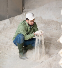 Farmer checks the quality of cornmeal in an animal feed warehouse