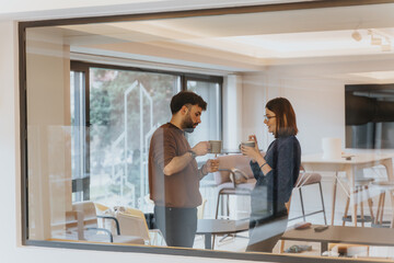 Two business young engaging in a casual coffee break conversation indoors.