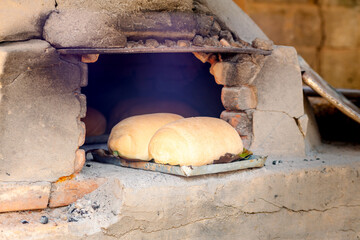 Freshly baked homemade bread in a rustic wood-fired oven. The image depicts the traditional...