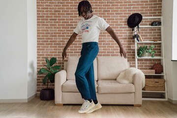 Man with dreadlocks wearing vintage clothing dancing at home