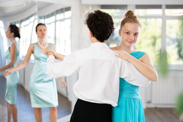 Motivated adolescent ballroom dancers, girl and boy in performance outfit practicing elegant dance...