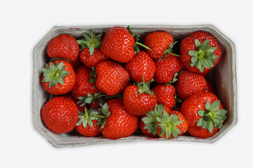 Freshly harvested ripe garden strawberries in recycled paper food container on a white background, top view close-up. Copy space.