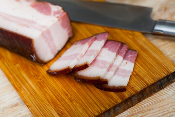Appetizing smoked lard on cutting board. On the kitchen table