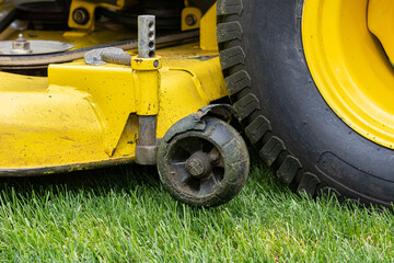 Lawn mower deck gauge wheel broken and damaged. Lawn equipment maintenance, repair, and service concept.