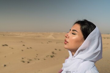 Arabic woman wearing white abaya in the desert