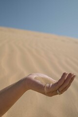 Female hand holding sand which is siffing through fingers